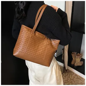Détail d'un grand sac cabas tissé marron avec texture point de croix et bandoulière