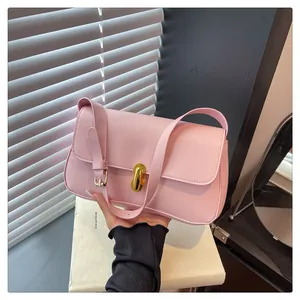 Detail of light pink shoulder bag featuring a gold metallic clasp and smooth leather texture