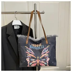 Détail du sac cabas en toile foncée avec imprimé papillon et bords effilochés