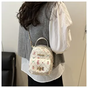 Detail of white mini backpack with cartoon prints and metallic FASHION logo plaque