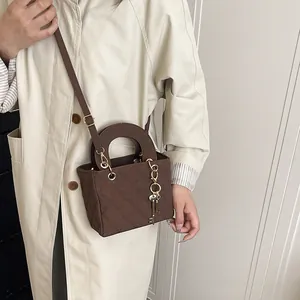 Brown quilted crossbody bag with circular handle and gold key pendant for autumn
