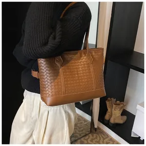 Détail d'un sac cabas en cuir tressé marron avec une texture vintage et une étiquette fine