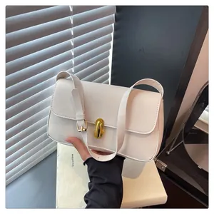 Close-up of cream shoulder bag featuring a polished gold metallic turn-lock closure