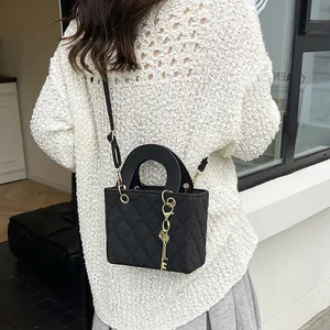 Chic black quilted crossbody bag with semi-circular handle and gold key charm accessory