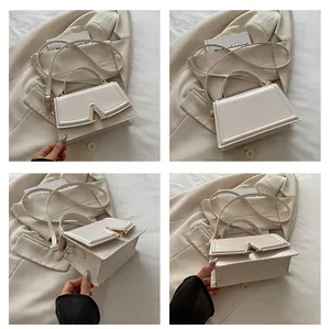 Detalle de bolso de mano crema con hebilla en V dorada y correa ajustable incluida