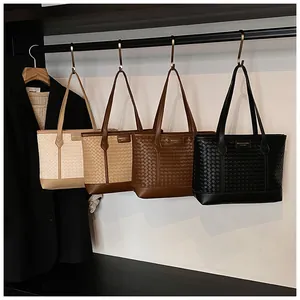 Détail de sacs cabas tressés en beige, marron et noir suspendus sur un portant