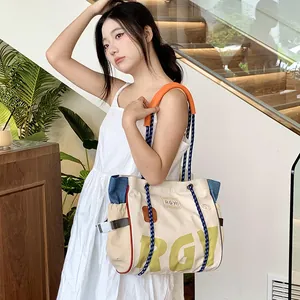 Detail of canvas tote bag showing contrast color stitching and knot shoulder strap
