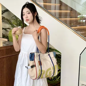 Detail of canvas tote bag with orange rope handles and printed letters on street setting