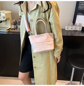 Pink pleated tote bag detail with detachable strap and brand logo in a cafe setting