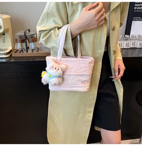 Detail of light pink tote bag with pleated texture and cute puppy charm accessory