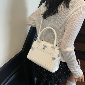 White pebbled leather handbag with silver twist lock and adjustable crossbody strap