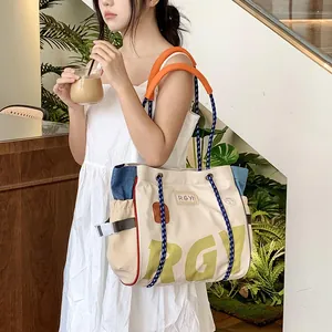 Detail of canvas tote bag with orange handles, blue climbing rope straps and RGY lettering