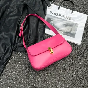 Hot pink leather underarm bag with gold metal clasp on a textured urban background