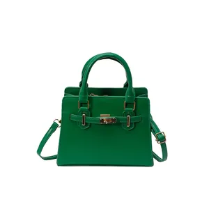 Green leather tote bag with gold buckle and adjustable strap on a white background