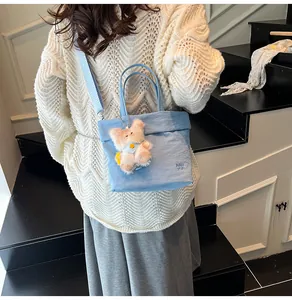 Detail of light blue canvas tote bag with RAH TOP embroidery and bear pendant detail
