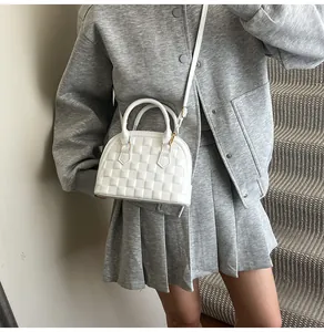 Detail of white embossed shell bag with checkerboard pattern and elegant metal zipper