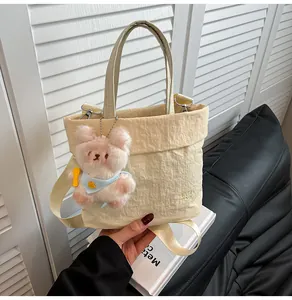 Close-up of yellow textured tote bag featuring RAH TOP embroidery and pink bear charm