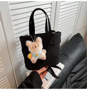 Close-up of black canvas tote bag featuring RAH TOP logo and cute plush animal charm