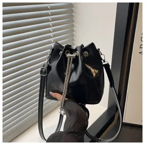 Detail of black glossy bucket bag with silver chain drawstring and pearl accents