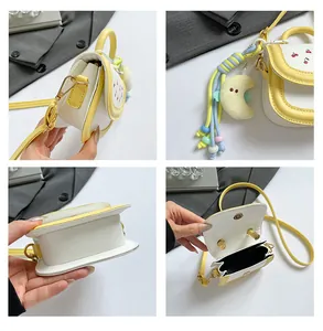 Detail view of mini crossbody bag with cherry embroidery and moon pendant accessory