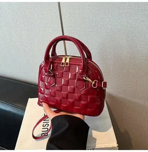 Detail of dark red patent leather shell bag featuring embossed checkerboard pattern and gold hardware