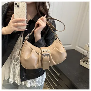 Détail du sac demi-lune beige plissé avec boucle argentée et texture brillante chic