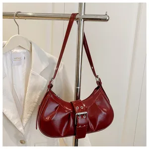 Détail du sac sous le bras en cuir verni rouge foncé avec boucle argentée en demi-lune