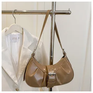 Détail du sac hobo en cuir verni kaki avec design plissé et grande boucle métallique