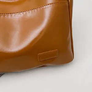 Dettaglio ravvicinato della borsa a secchiello in ecopelle marrone con cuciture
