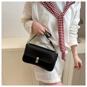 Detail of minimalist black rectangle shoulder bag with metallic gold press-lock closure