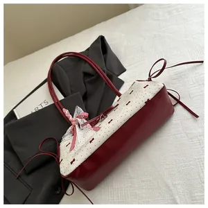 Gros plan d'un sac à bandoulière avec nœud rouge élégant et design bicolore en similicuir