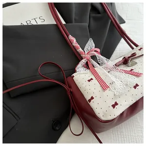 Détail du sac à nœud rouge et blanc avec pendentif cœur et bordure en dentelle