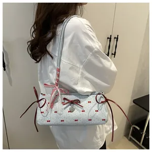 Détail du sac bandoulière bleu clair avec imprimés nœuds rouges et pendentif coeur