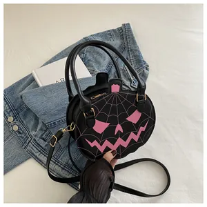 Close-up of black leather pumpkin bag with pink spider web and gold zipper detail