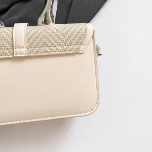 Close-up of beige woven fabric and smooth leather texture on a minimalist handbag