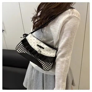 Close-up of lace bow underarm bag with silver heart pendant and plaid stitching detail