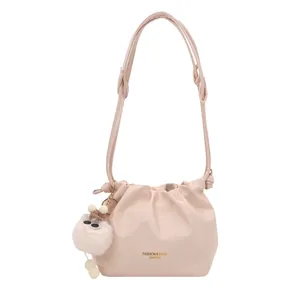 Bolso cubo plisado beige con un pompón blanco suave y correa ajustable de moda