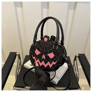 Detail of pumpkin-shaped crossbody bag with pink spider web and carved face design
