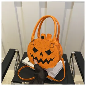 Detail of a chic orange pumpkin crossbody bag with spider web design on a black chair