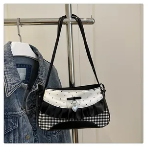 Close-up of lace edge, polka dots, and silver heart pendant on a sweet vintage shoulder bag