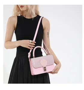 Detalle de bolso rosa con solapa de purpurina y logo circular sobre vestido negro