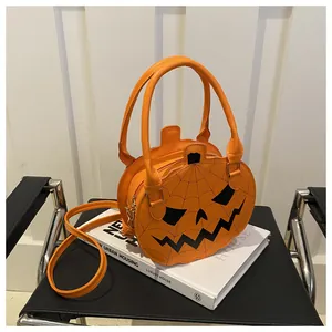Detail of a bright orange pumpkin-shaped handbag with Jack-o'-lantern face and spider web