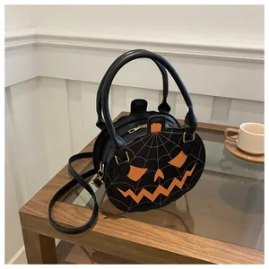 Detail of pumpkin crossbody bag with orange jack-o-lantern face and spider web sewing