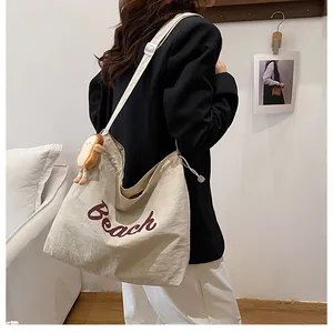 Detail of off-white canvas tote with Beach lettering and cute plush bread pendant