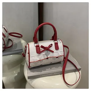 Detail of red bow, heart charm and pleated ruffles on butterfly print underarm bag