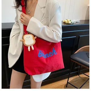 Red canvas tote bag with blue Beach lettering and cute toast plush charm detail