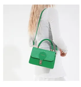 Detail of the bright green crossbody bag with woven texture flap and metallic press lock