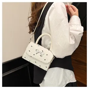 Détail du sac à bandoulière blanc avec imprimé nœuds noirs et fermoir nœud argenté