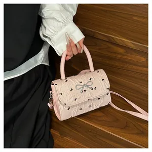 Détail d'un sac plissé rose clair avec imprimés nœuds noirs et fermoir métallique argenté