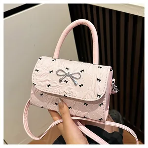Détail du mini sac plissé rose avec imprimés nœuds noirs et boucle métallique argentée